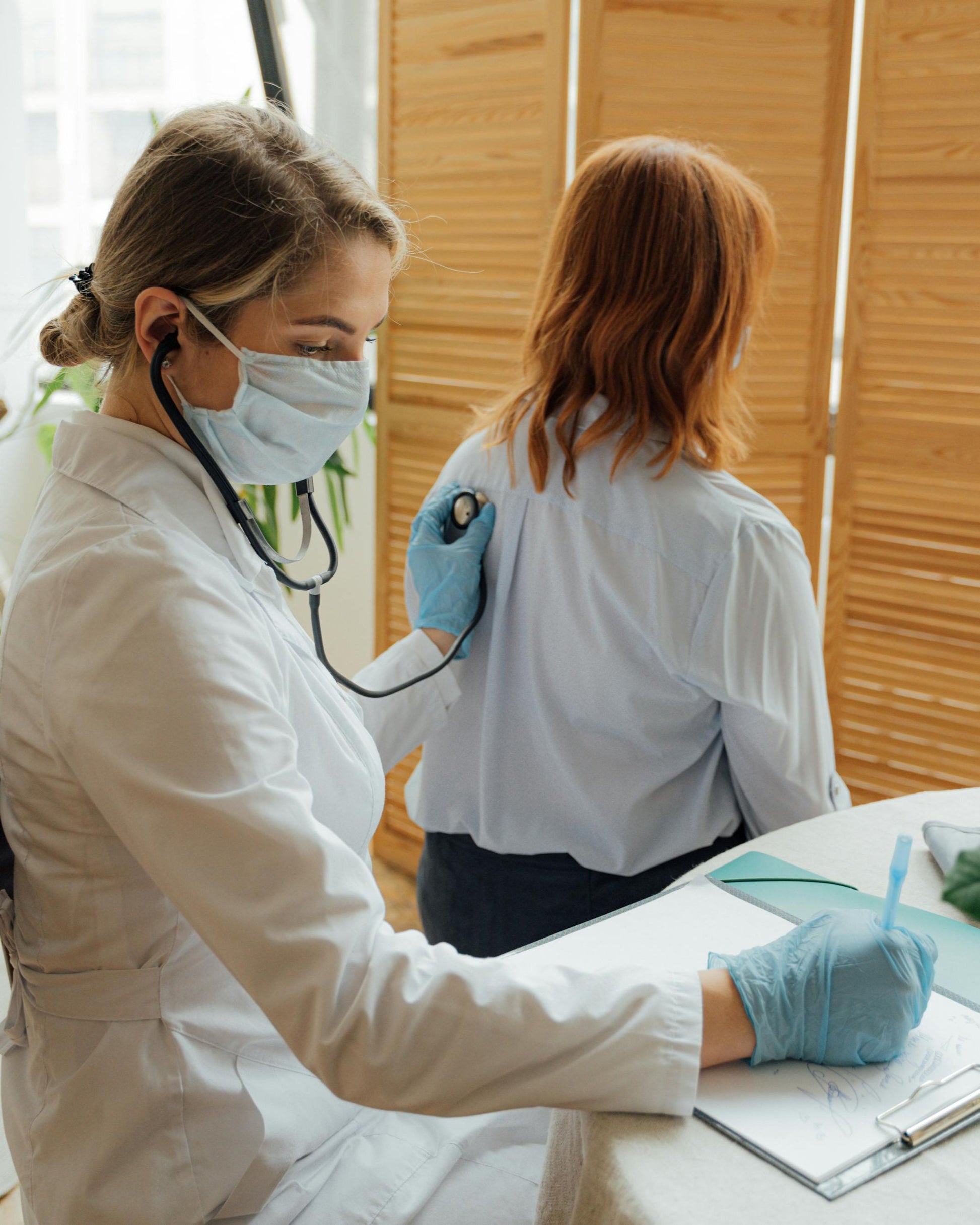 A doctor using a stethoscope on a patient's back.