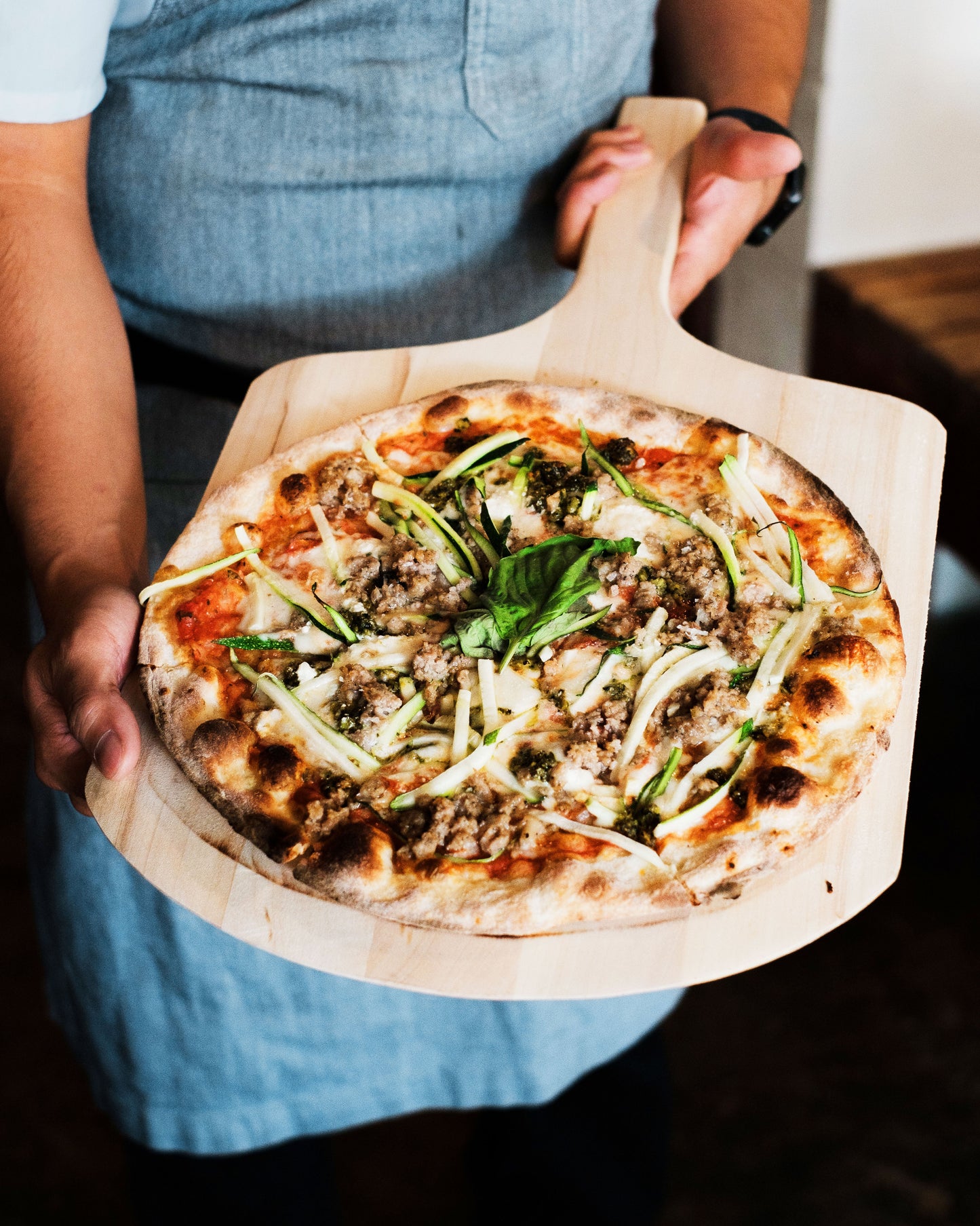 A chef showing their pizza fresh out of the oven.