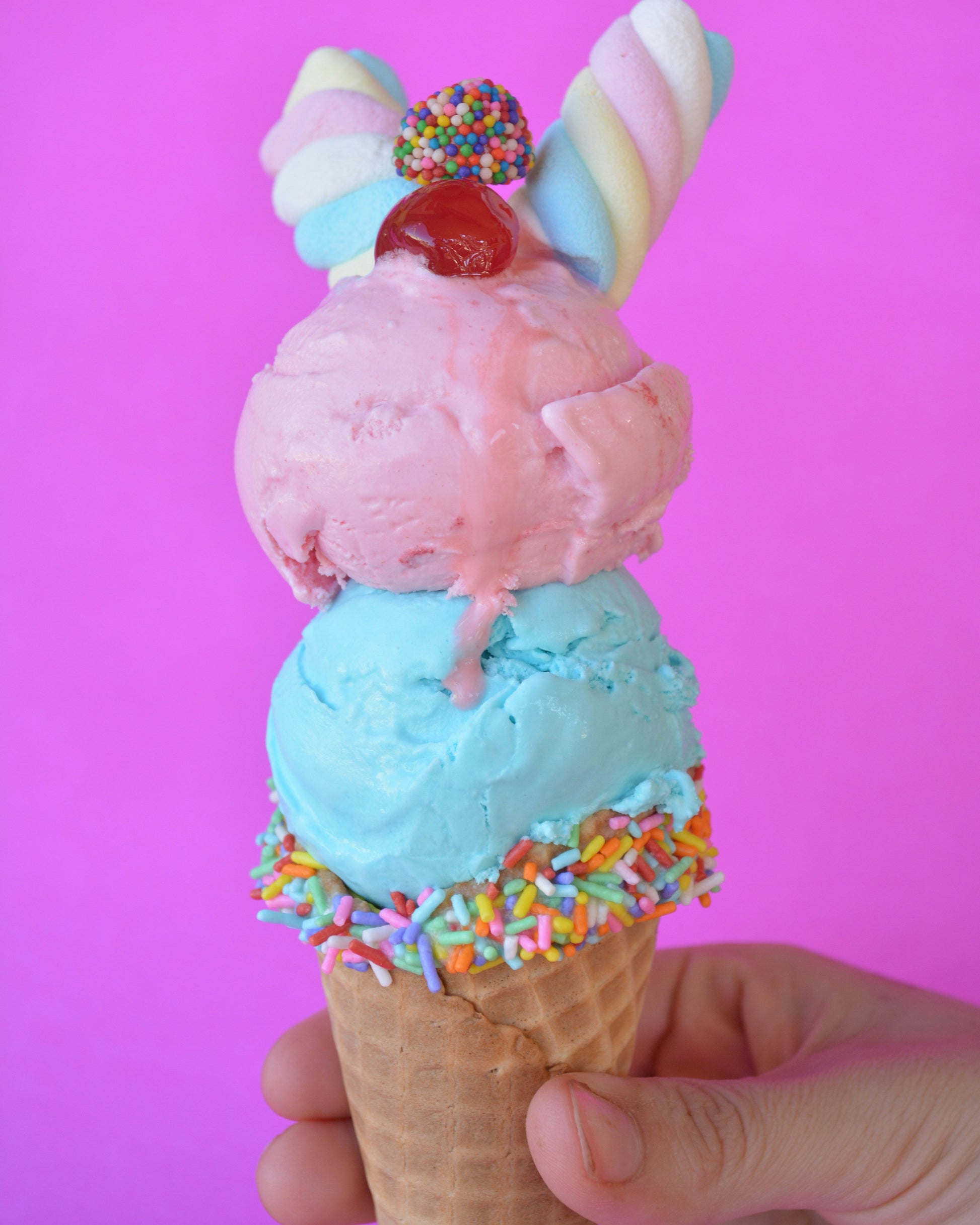 Two scoops of ice cream served in a cone with sprinkles 