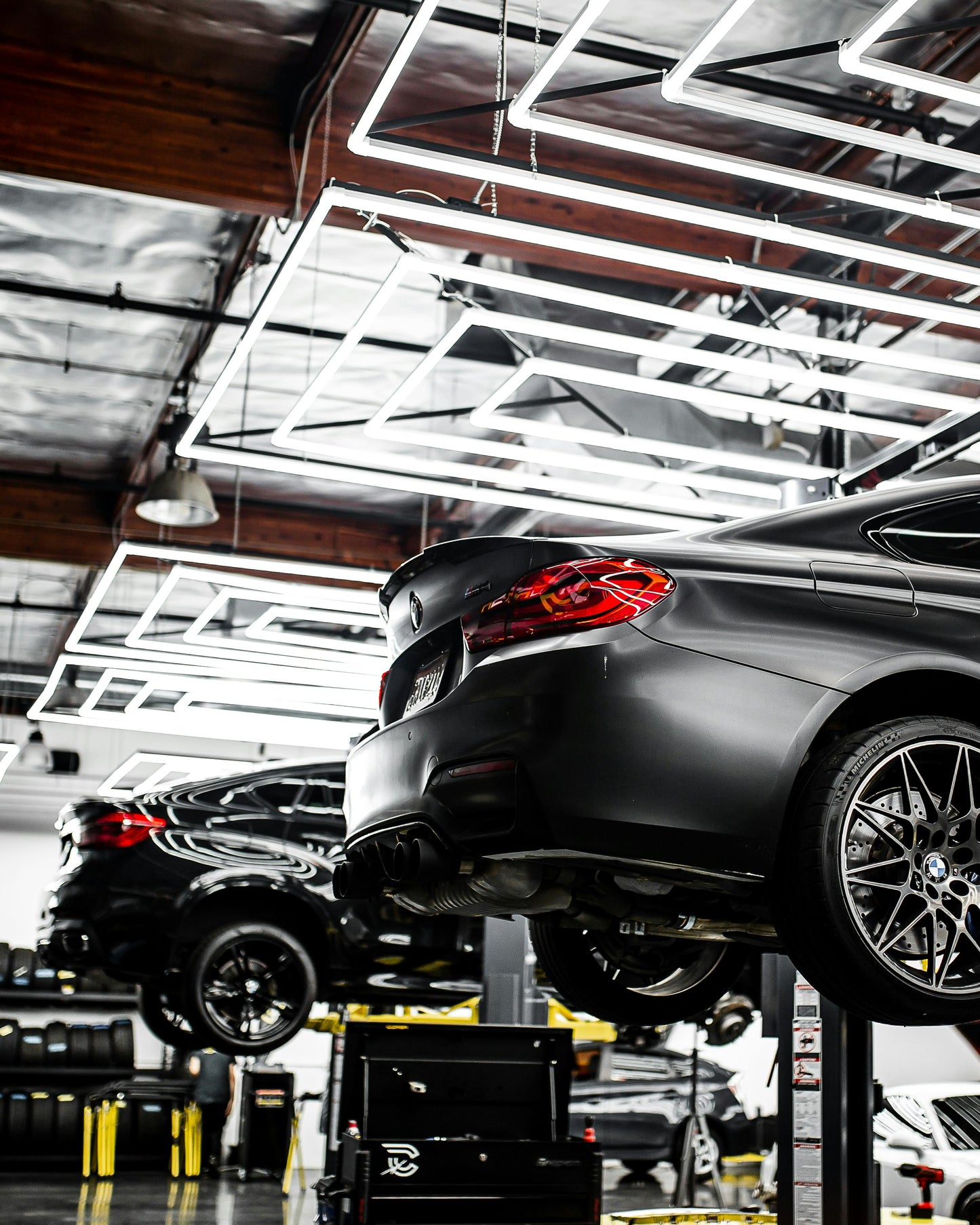 Two cars on vehicle lifts inside auto repair shop