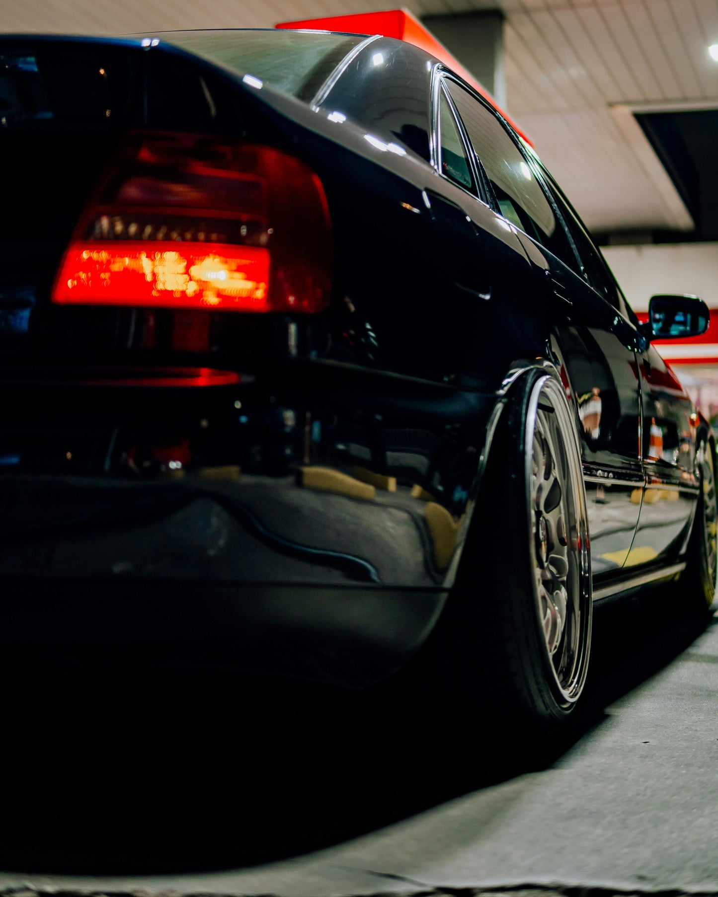 Black car parked inside a garage with red accents